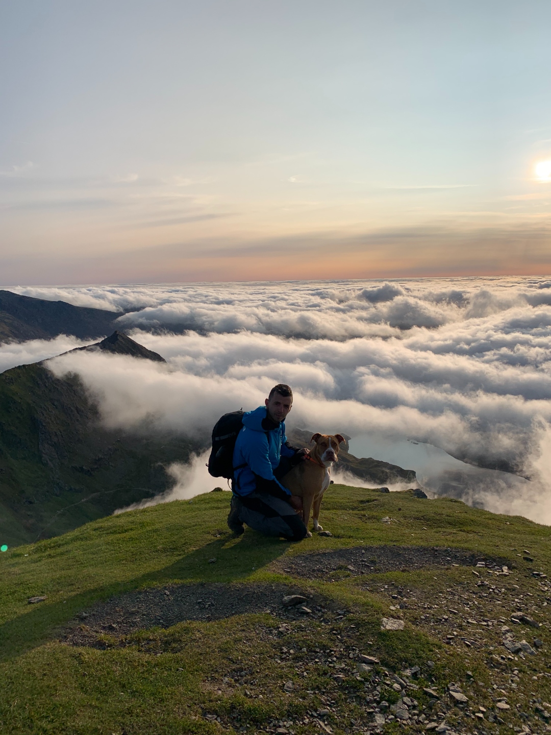 Patrick on a mountain with his dog above the clouds